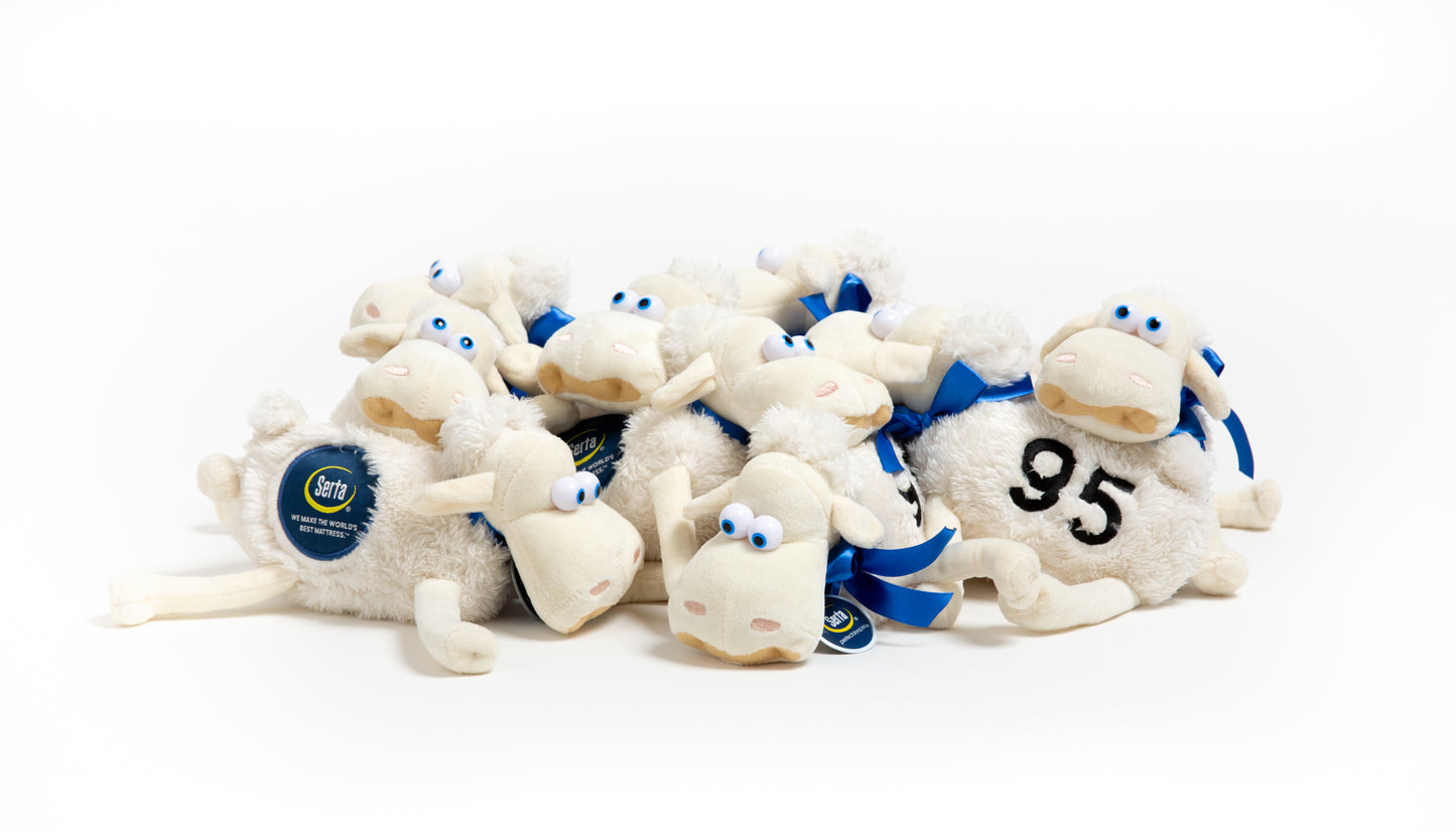Stack of white Seta plush sheep toys with blue ribbons and a number 95 on a white background
