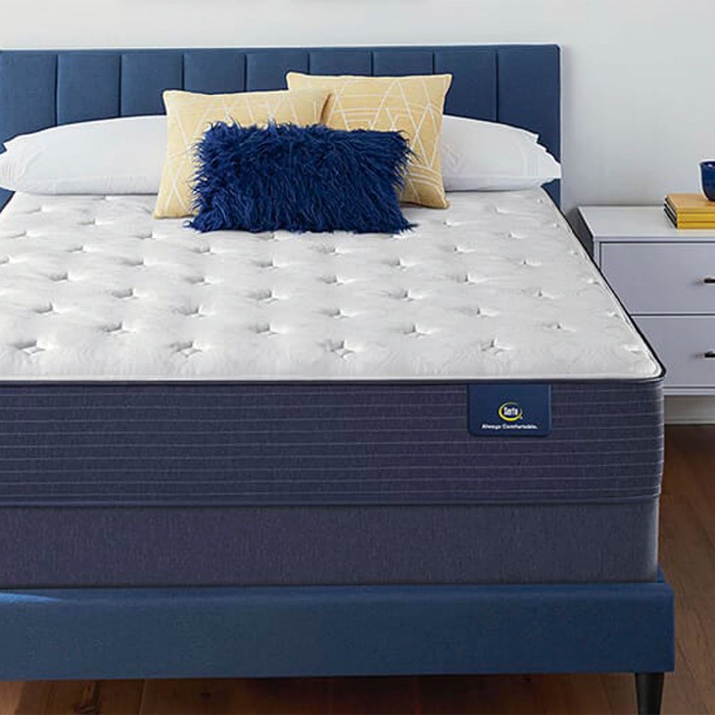 The Serta Classic Plush 11" in a bedroom, on a blue bed next to a white table