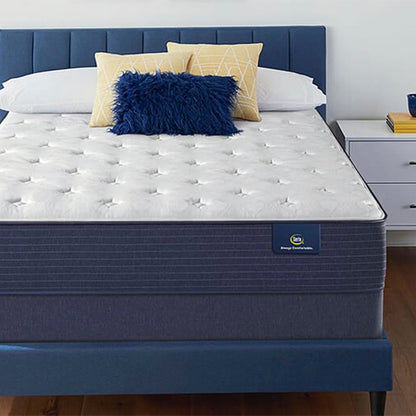 The Serta Classic Plush 11" in a bedroom, on a blue bed next to a white table