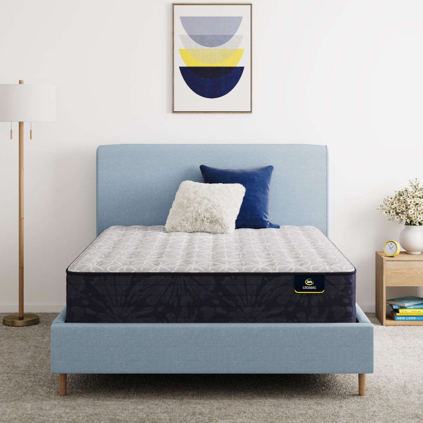 Serta Classic Clarks Hill Mattress on a bed with a blue headboard and decorative pillows in a bedroom setting.