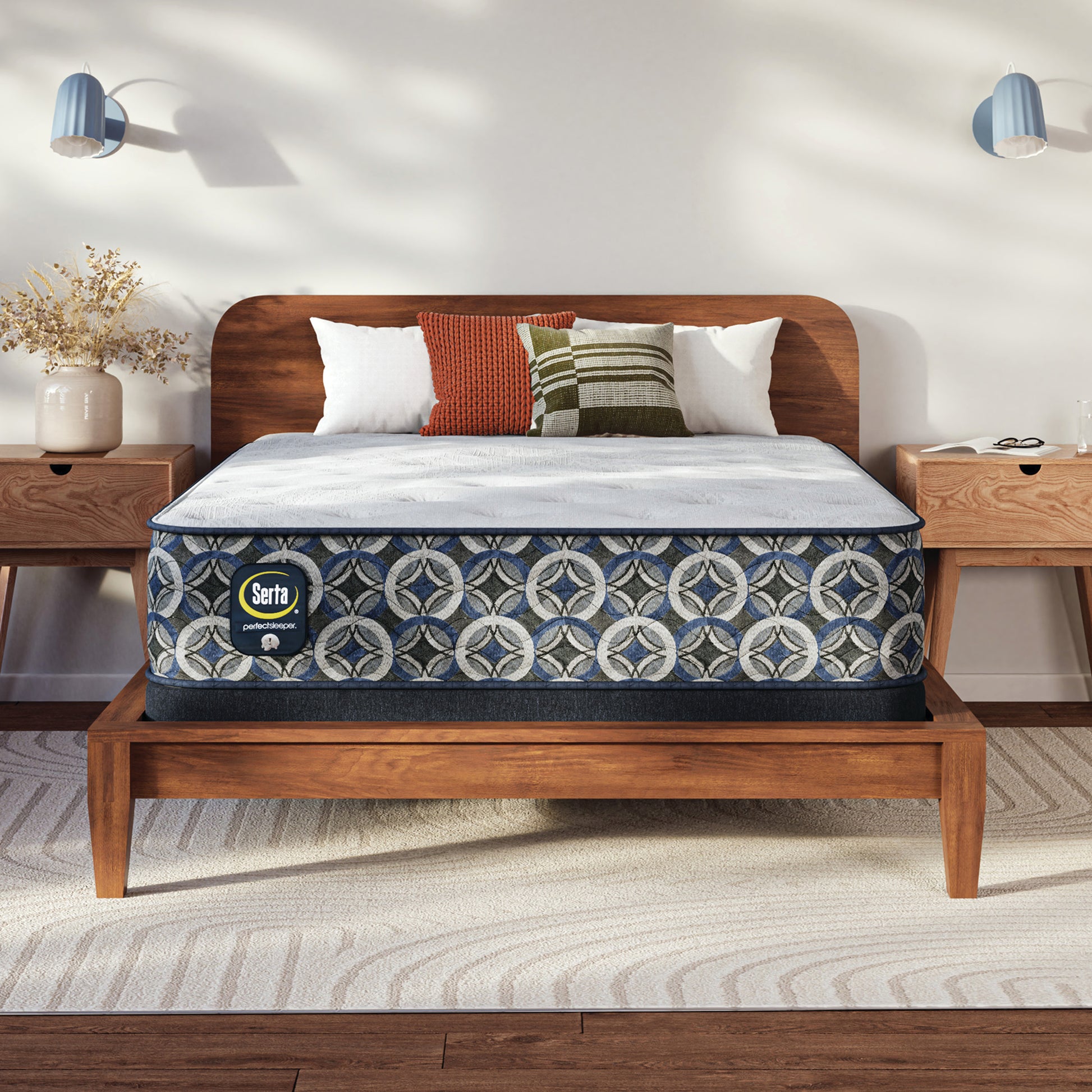 Serta Perfect Sleeper plush mattress on a wooden bed frame with decorative pillows in a bedroom setting.