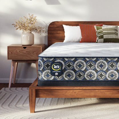 Serta Perfect Sleeper plush mattress on a wooden bed with decorative pillows and a nightstand in a bedroom setting.