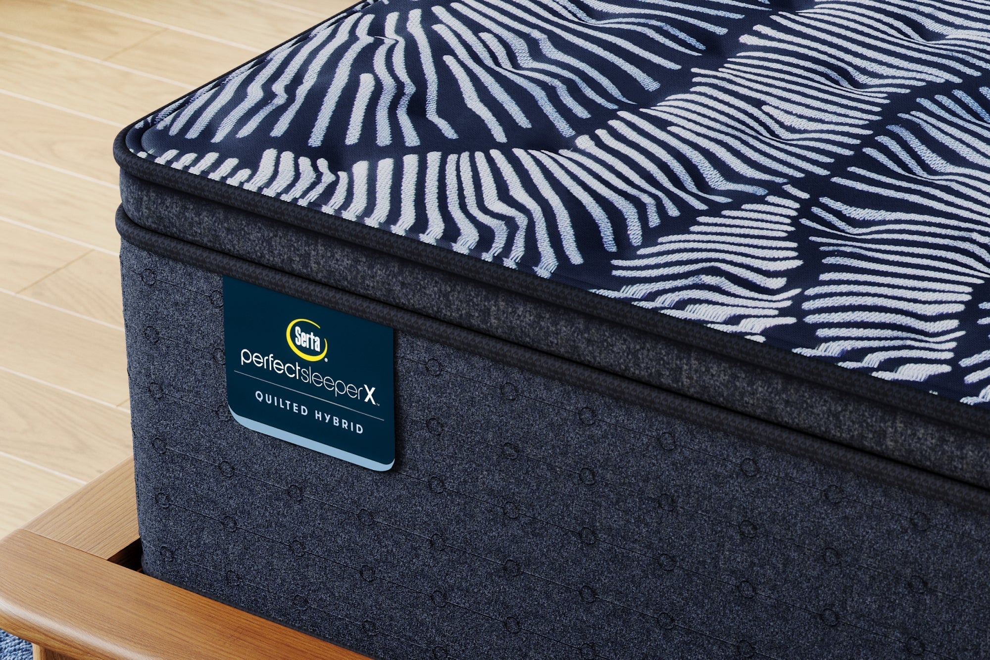 Close-up of a Serta Perfect Sleeper X Quilted Hybrid mattress with a medium pillow top, showcasing its zoned coils and graphite-infused memory foam.