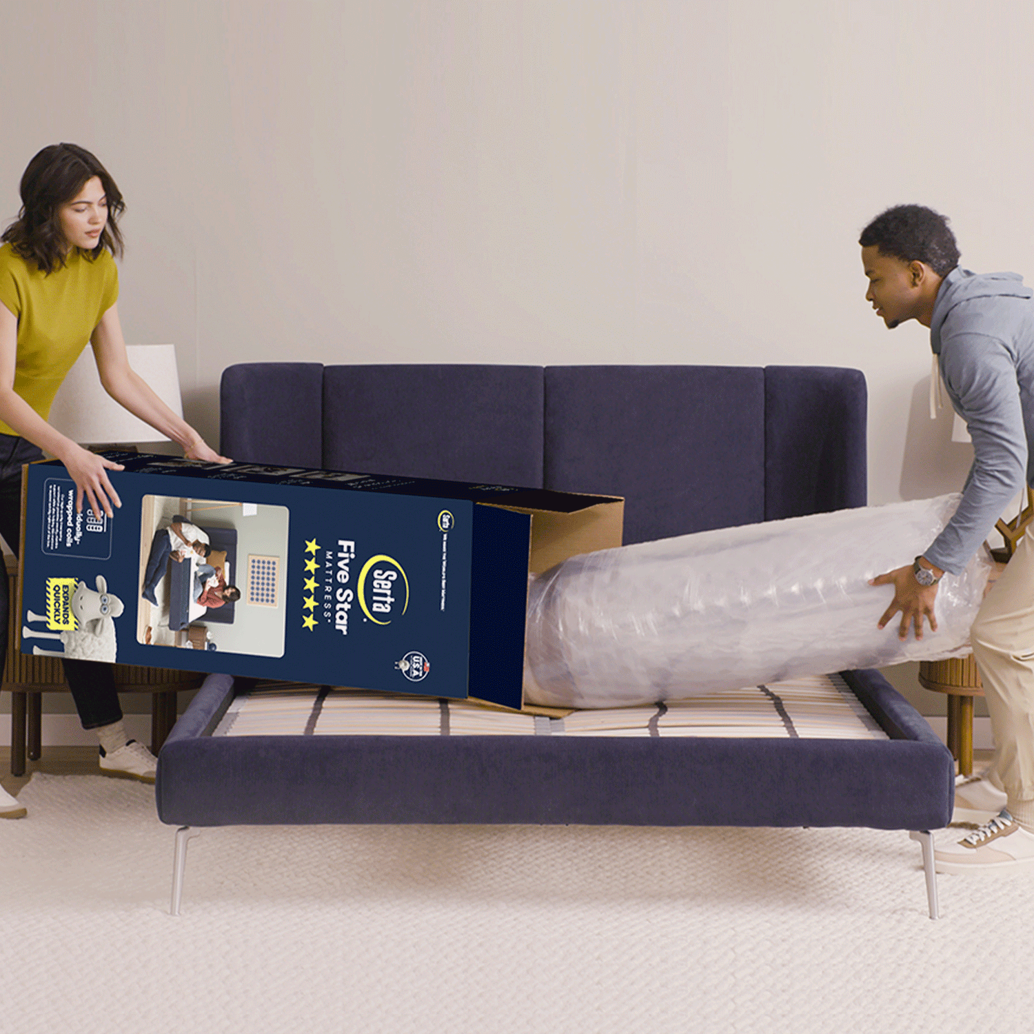 Gif video of a couple opening a mattress in a box, unrolling it and then laying on it.