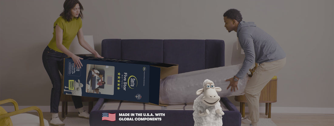 Man and woman unpacking a Serta Five Star Mattress in a box with the Serta Sheep raising its hoofs under 5 yellow stars 